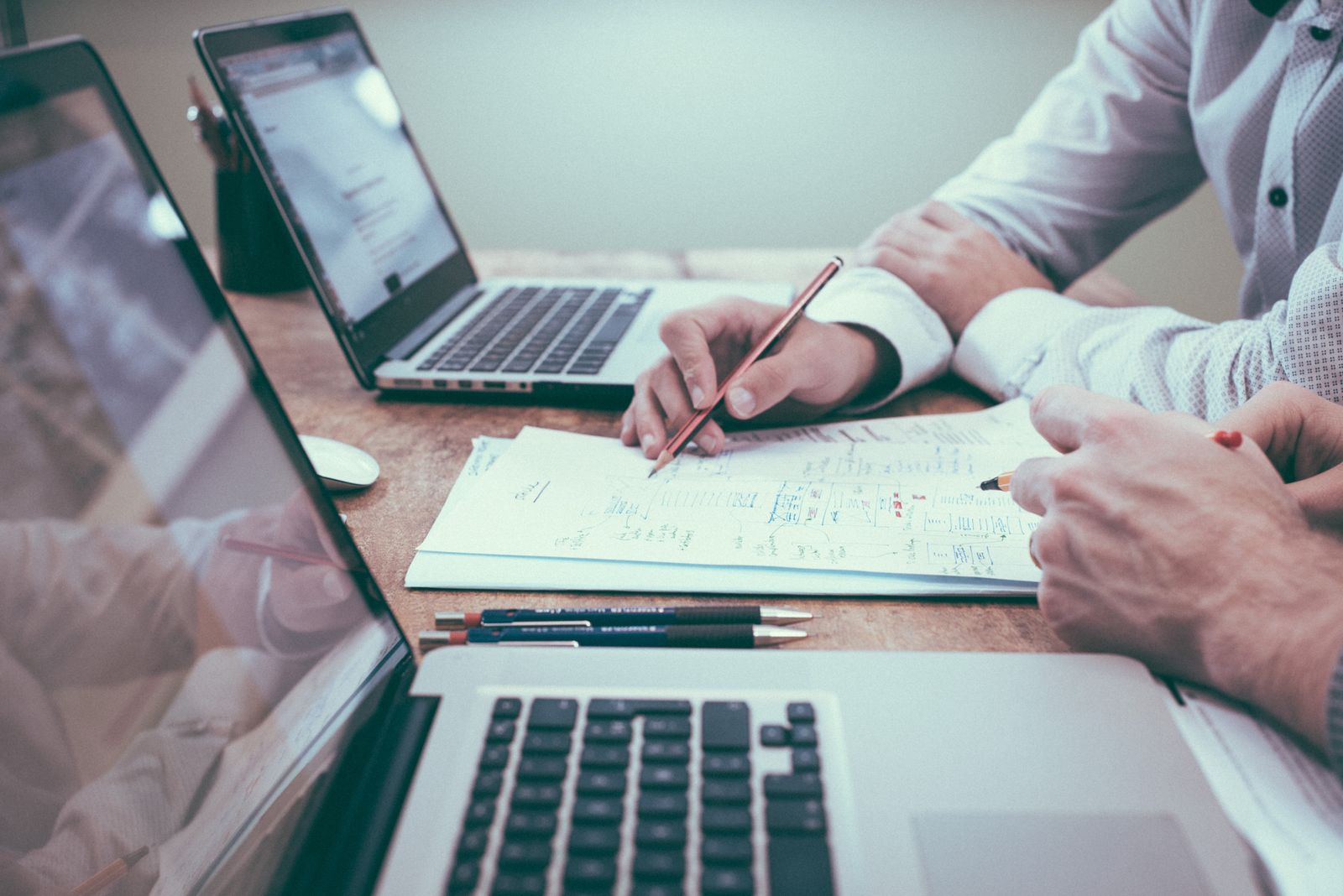 Zwei Personen arbeiten mit Laptops an einem annotierten Plan